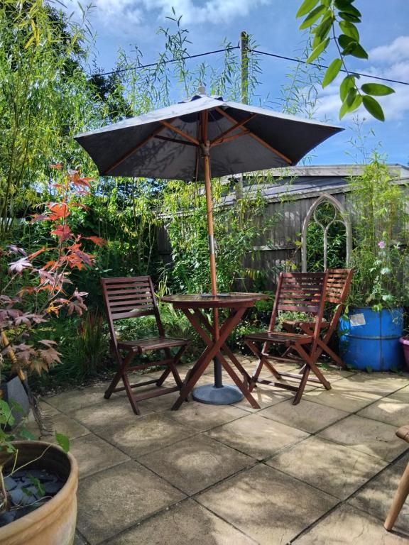a picnic table and two chairs under an umbrella at Llety'r Post in Crickhowell