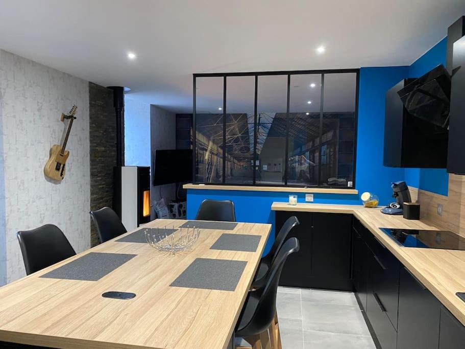 - une cuisine avec une table en bois, des chaises et une guitare dans l'établissement Jolie maison rénovée, à Poulangy