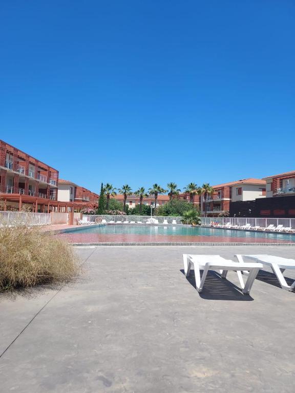 2 tables de pique-nique blanches assises dans un parking dans l'établissement Les demeures de la massane, à Argelès-sur-Mer