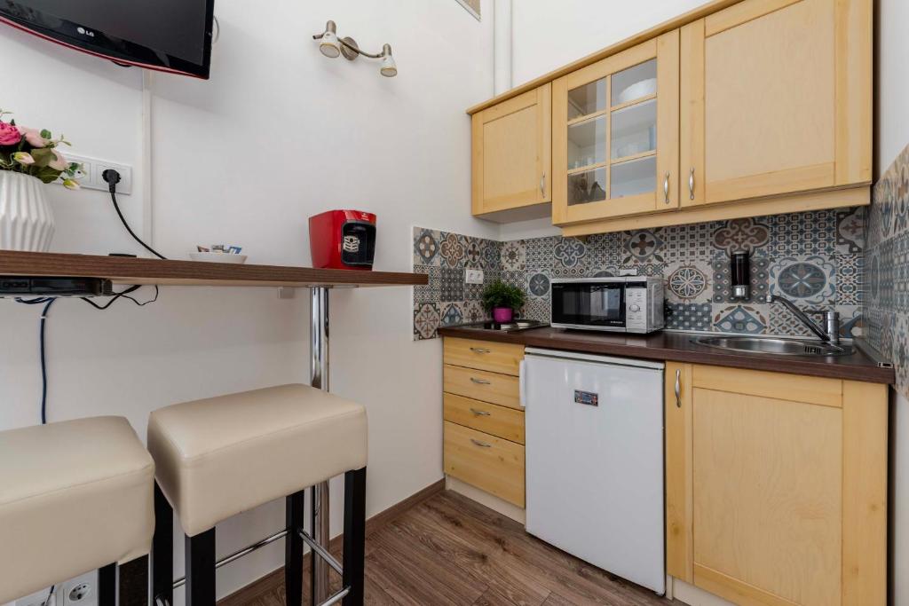 a small kitchen with wooden cabinets and a microwave at Mirage Apartments Váci Street in Budapest
