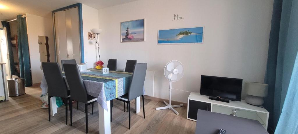 une salle à manger avec une table, des chaises et une télévision dans l'établissement Marina, au Barcarès