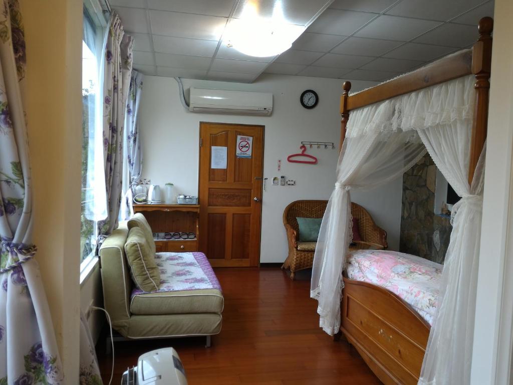 a bedroom with a canopy bed with a couch and a chair at Liang Chen Mei Jin B&amp;B in Shuangxi