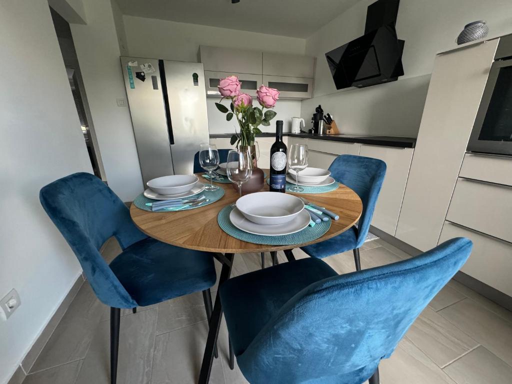 una mesa de comedor con sillas azules y una botella de vino en Apartment Tomy, en Rijeka