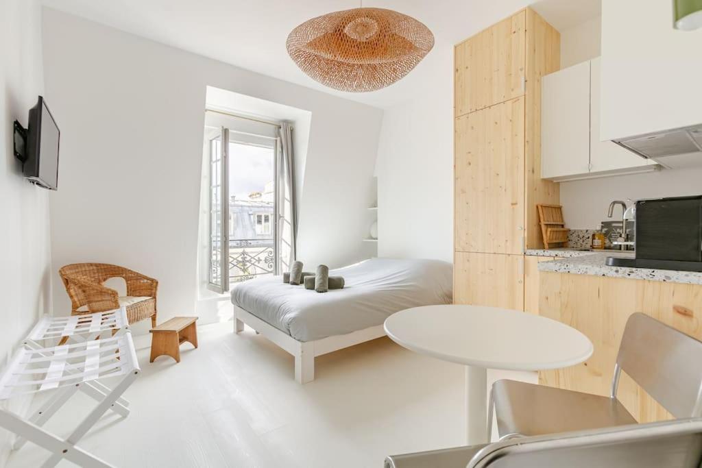 une chambre blanche avec un lit et une table dans l'établissement Charming Studio Ideally Located in Paris, 9th, à Paris
