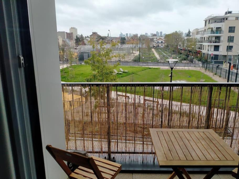 d'un balcon avec une table et une vue sur un parc. dans l'établissement Bel appartement proche Paris, à Bois-Colombes