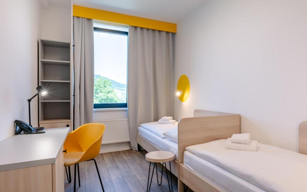 a room with two beds and a desk and a window at Hotel Active Stadium in Lovosice