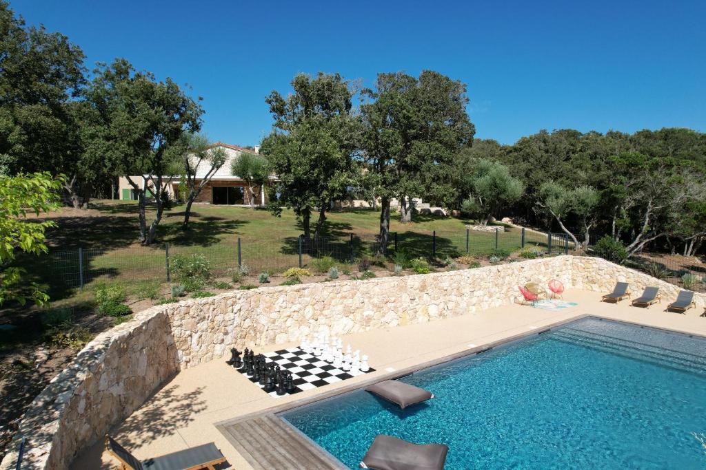 a swimming pool with a stone wall next to a house at Villa Arbevhio in Bonifacio