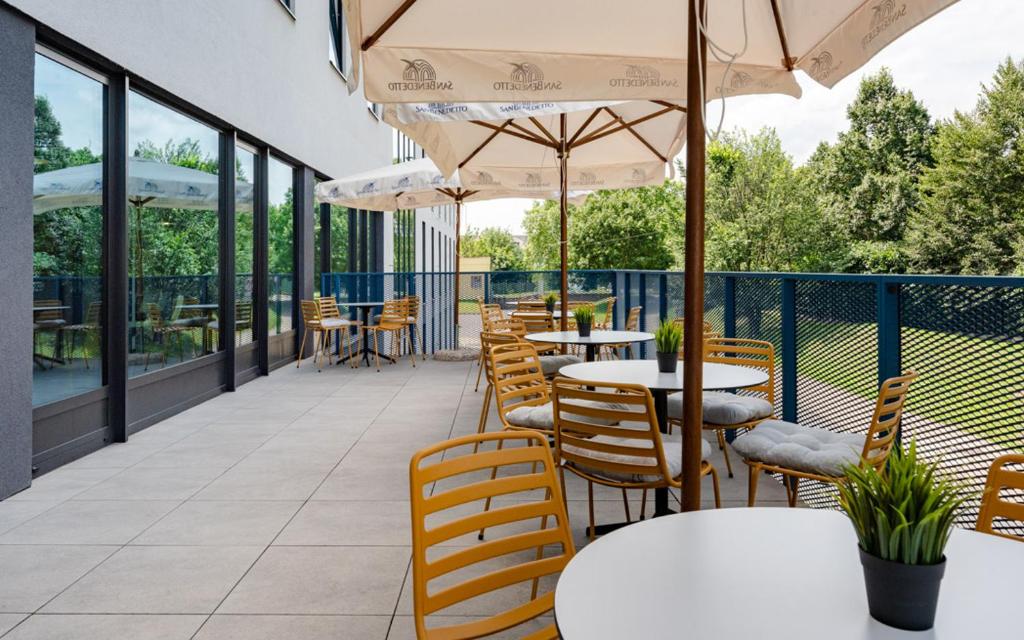 an outdoor patio with tables and chairs and umbrellas at Hotel Active Stadium in Lovosice