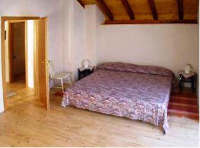 Schlafzimmer mit einem Bett und Holzboden in der Unterkunft Casa Elin in Maggia