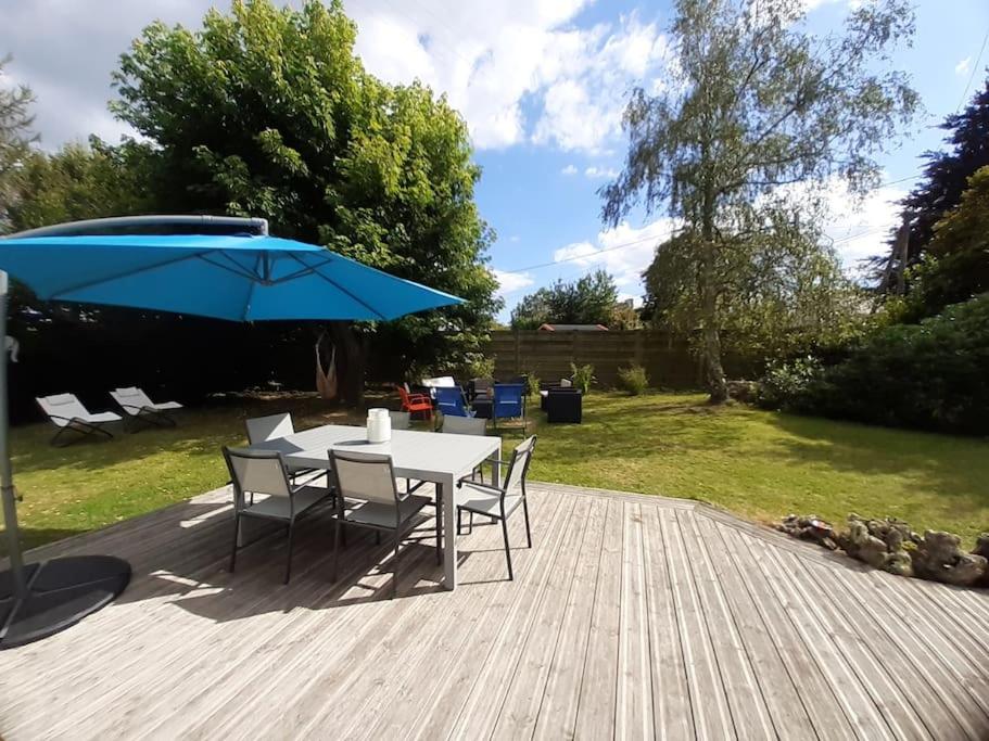 une table et des chaises avec un parasol bleu sur une terrasse dans l'établissement Maison au calme proche de la mer Fouesnant Cap Coz, à Fouesnant