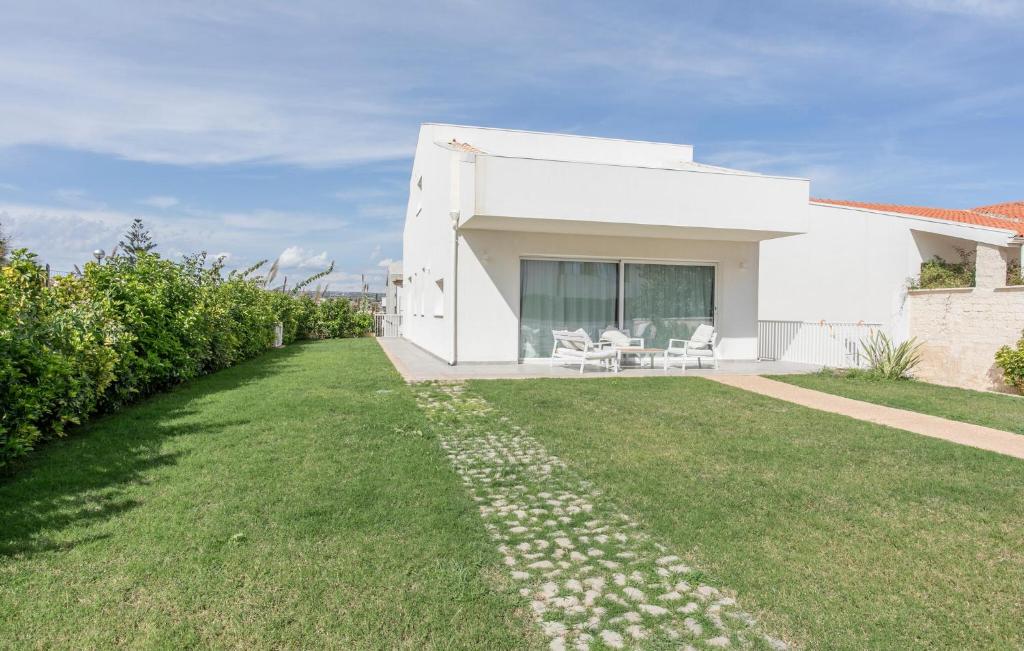 ein weißes Haus mit grünem Rasen davor in der Unterkunft Amazing Apartment In Marina Di Modica in Marina di Modica