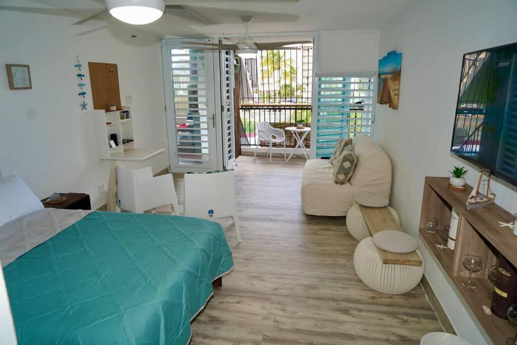 um quarto com uma cama azul e uma sala de estar em Relaxing Studio Near El Yunque With Pool View em Luquillo