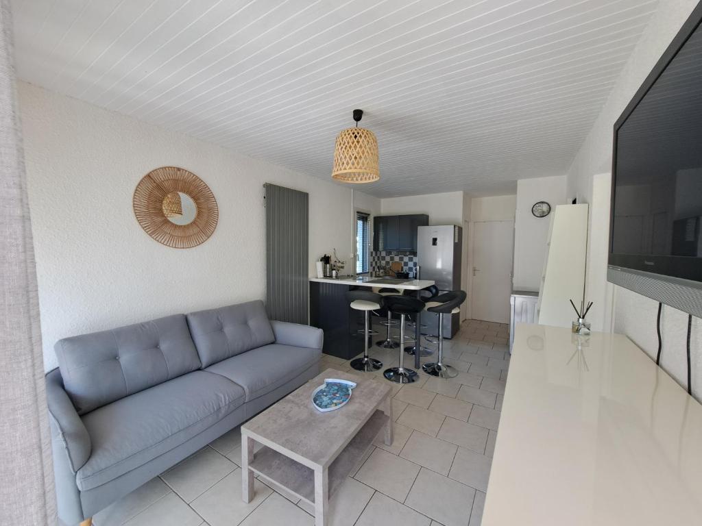 un salon avec un canapé bleu et une cuisine dans l'établissement Cottage au cœur des Landes, à Lit-et-Mixe