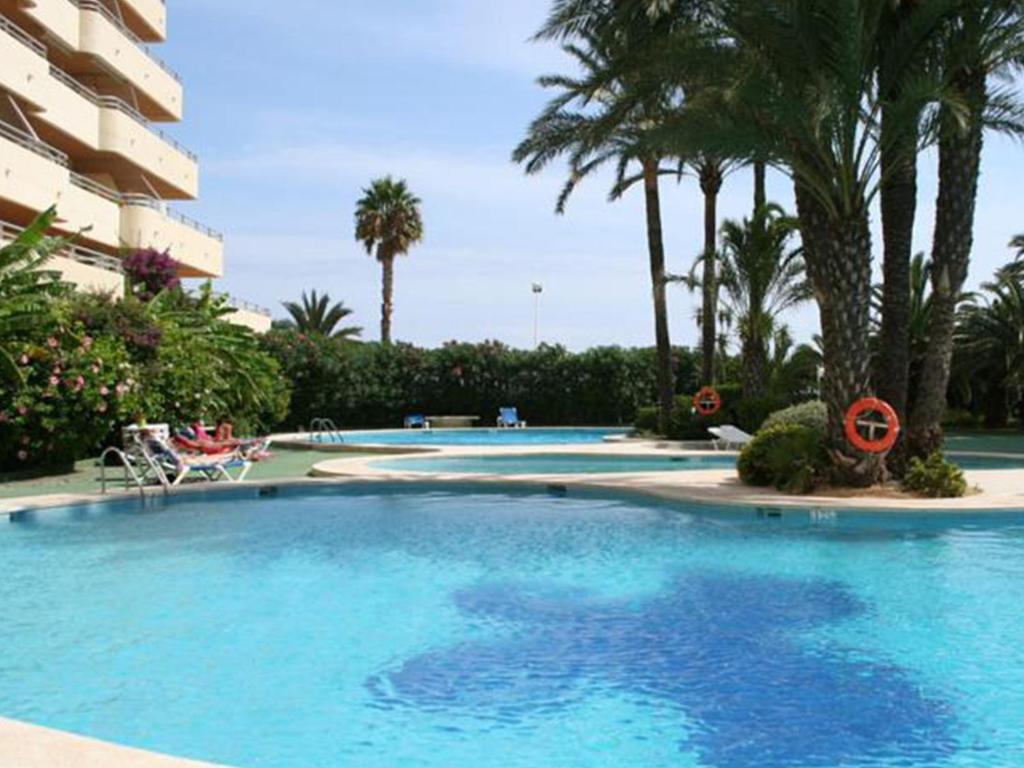 una gran piscina con palmeras y un edificio en Apartamentos Turmalina Unitursa, en Calpe