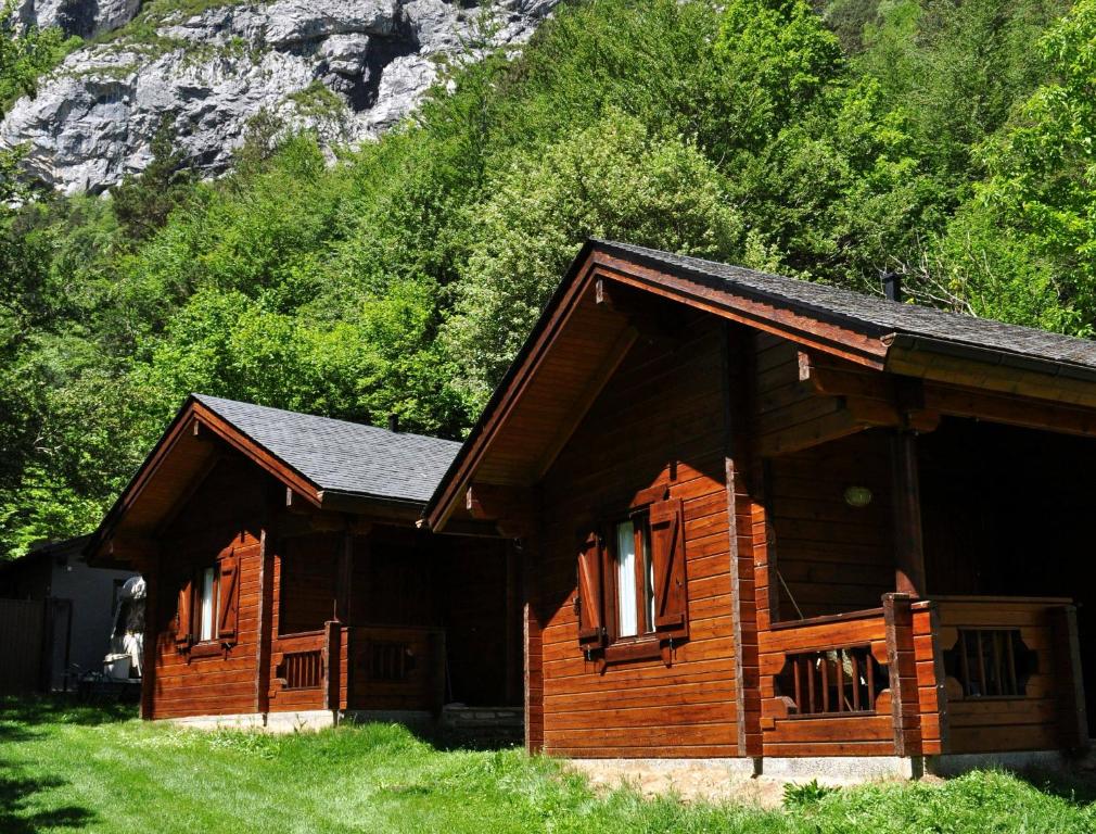 a log cabin in the grass next to a mountain at Camping Valle de Bujaruelo in Torla-Ordesa