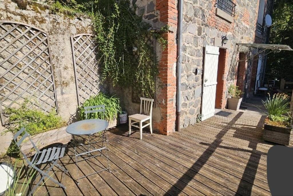 une terrasse en bois avec une table et des chaises dessus dans l'établissement Appartement au cœurs d'Aurillac, à Aurillac