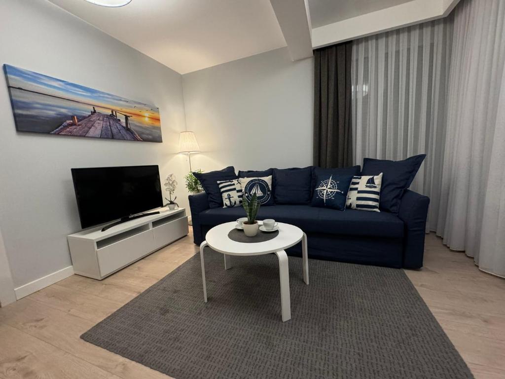 een woonkamer met een blauwe bank en een tafel bij Rewal Cliff Morska 1 in Rewal
