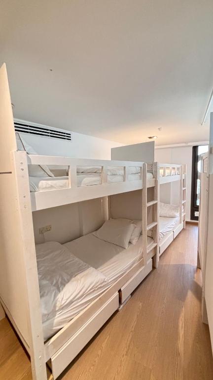 2 weiße Etagenbetten in einem Zimmer in der Unterkunft Ora Place JBR in Dubai