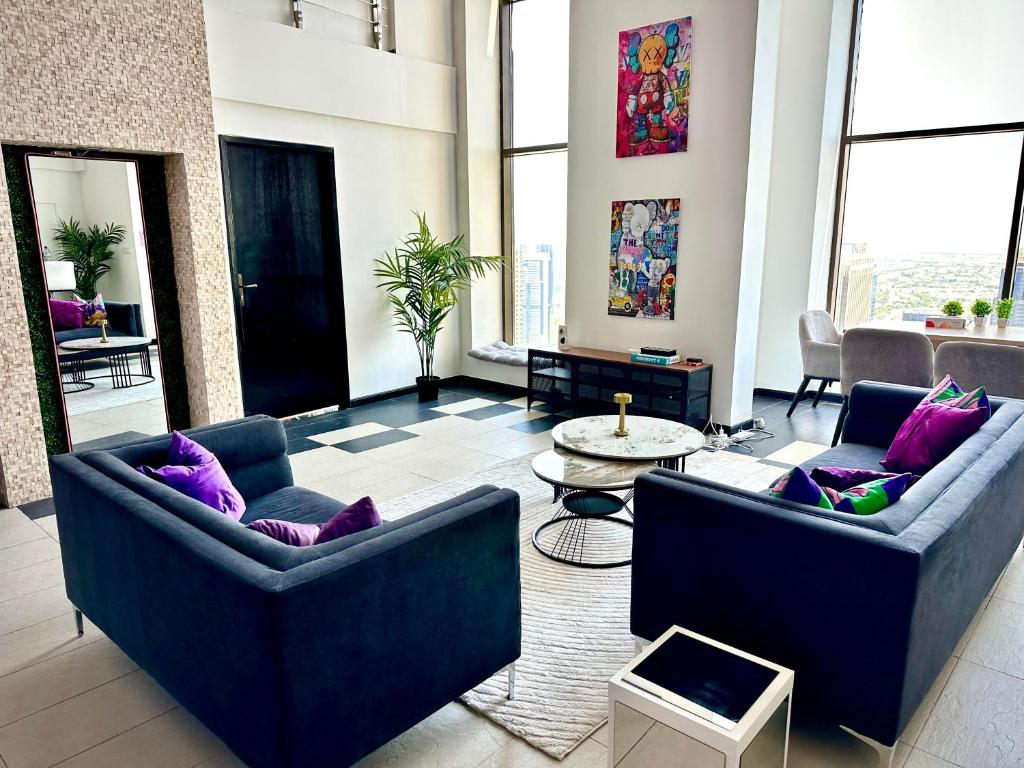ein Wohnzimmer mit zwei blauen Sofas und lila Kissen in der Unterkunft Ora Place JBR in Dubai