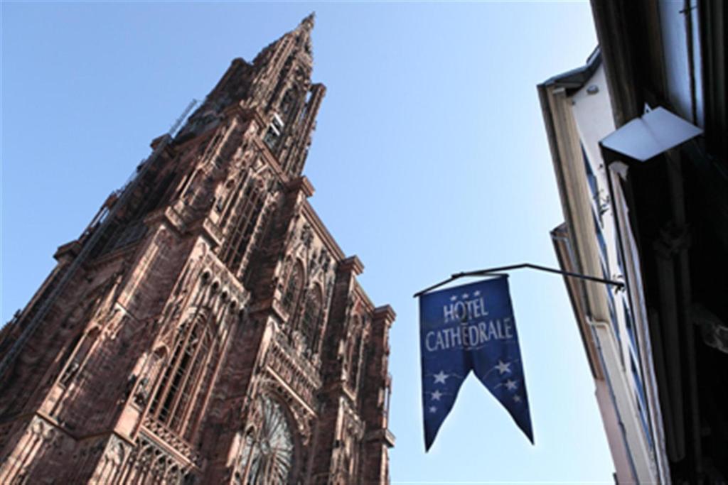 una torre del reloj con una bandera frente a un edificio en Hotel Cathédrale, en Estrasburgo