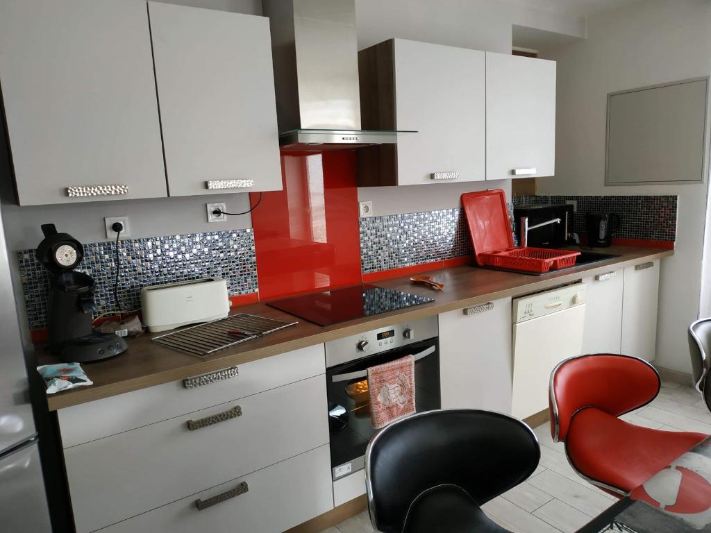 een keuken met witte kasten en rode stoelen bij Maison Noyarey in Noyarey