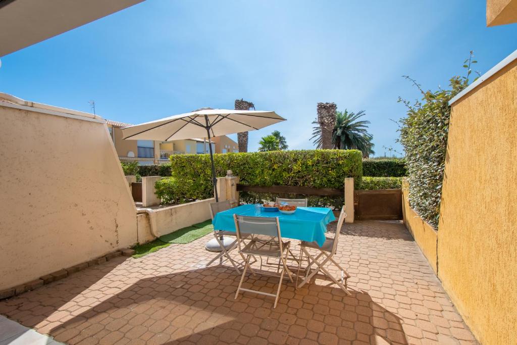 a blue table with chairs and an umbrella on a patio at Le Brise Marine - Terrasse - Plage - Piscine - Parking in Cap d'Agde
