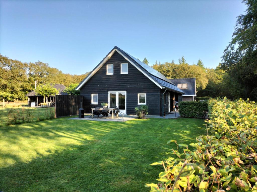 a black house with a yard in front of it at De Heide in Wijnjewoude