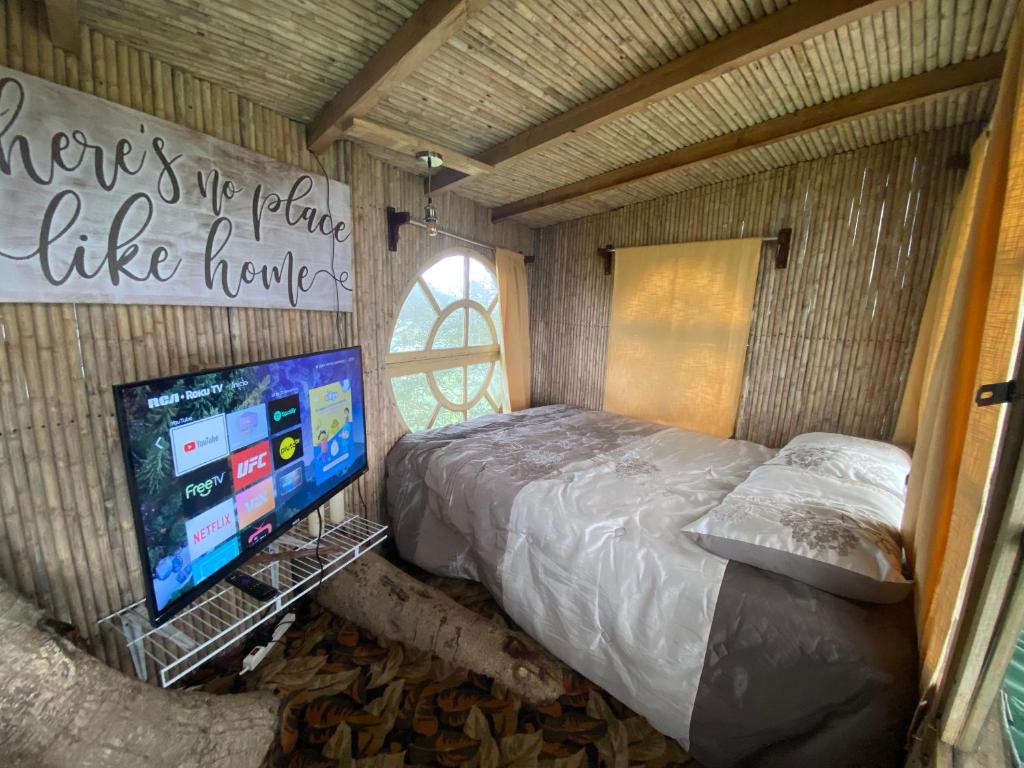 NaranjoにあるCasa del Arbol Feel Goodのベッドとテレビのある寝室