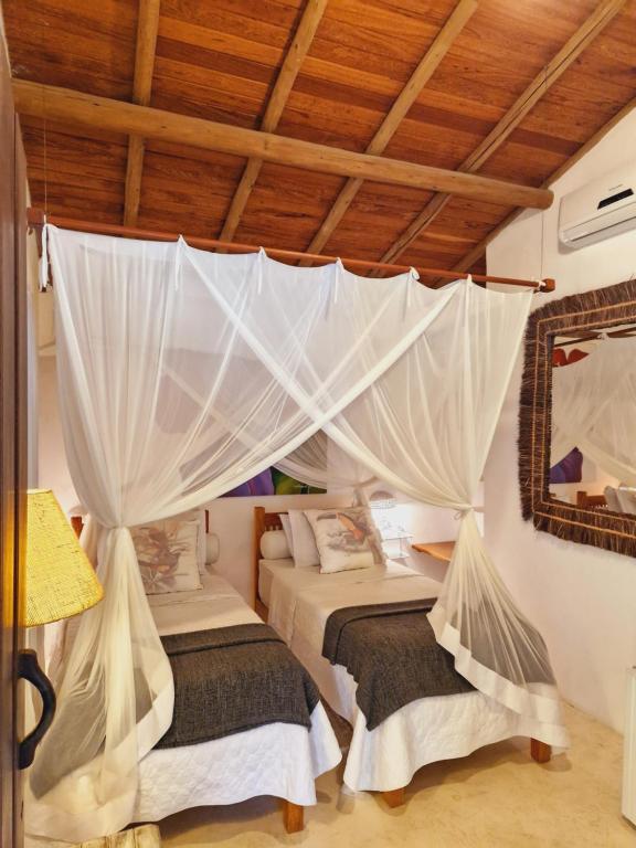 a bedroom with two beds with mosquito nets at Mini Casa com Jacuzzi e Piscina in Trancoso