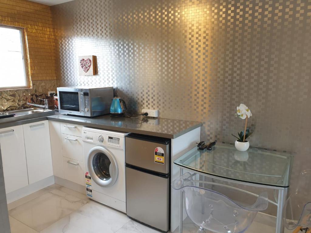 a kitchen with a washing machine and a microwave at Cute comfortable, quiet studio 11 with Carpark in Auckland