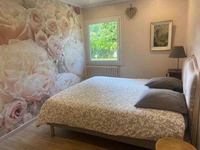 - une chambre avec un lit orné de fleurs sur le mur dans l'établissement Parenthèse Océane Suite calme 1 ou 2 chambres entre bois et mer, à Perros-Guirec