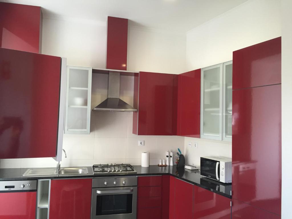 a kitchen with red cabinets and a stove at MODERN Conde Barão - SSs Apartments in Lisbon