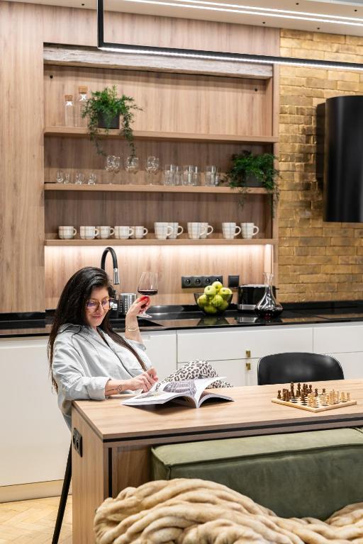 a woman sitting at a kitchen counter holding a glass of wine at Helska 11 - Apartamenty blisko plaży i Monte Cassino - topowy adres by Lion Apartments in Sopot