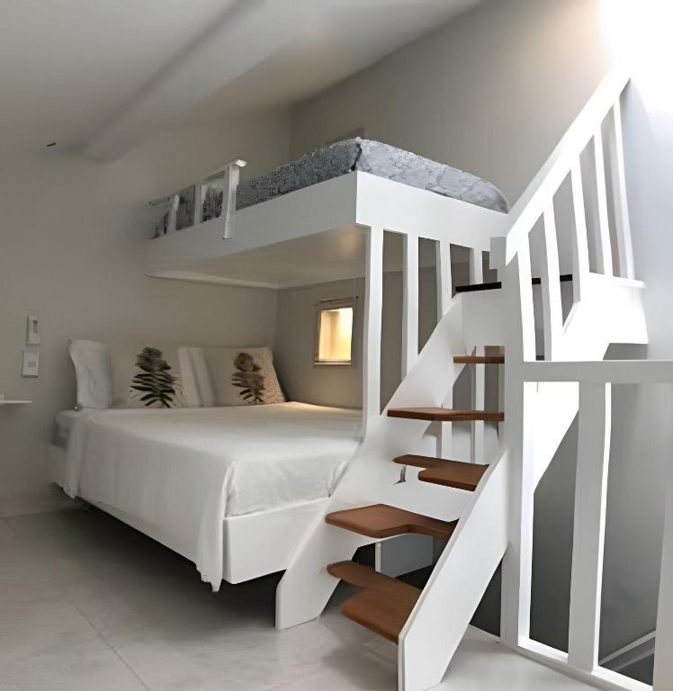 Un dormitorio con una litera blanca y una escalera. en Studio lindo nas Rua das Pedras, en Búzios