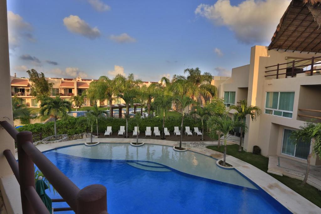 Blick auf einen Pool mit Stühlen und ein Gebäude in der Unterkunft Coral Maya Stay Suites in Puerto Aventuras