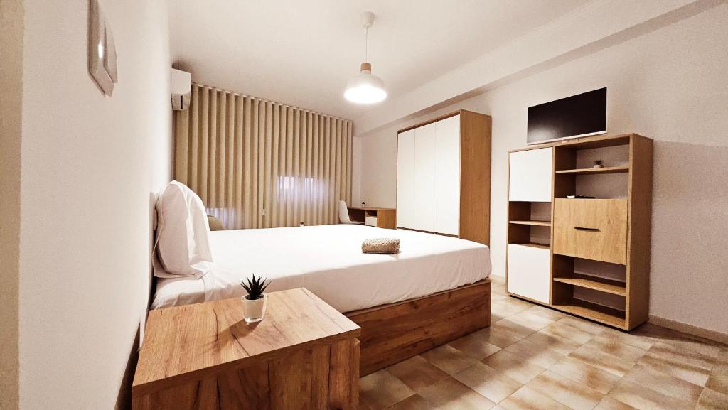 ein Schlafzimmer mit einem Bett, einem Fernseher und einem Tisch in der Unterkunft Rooms4you 3 in historic center of Braga in Braga