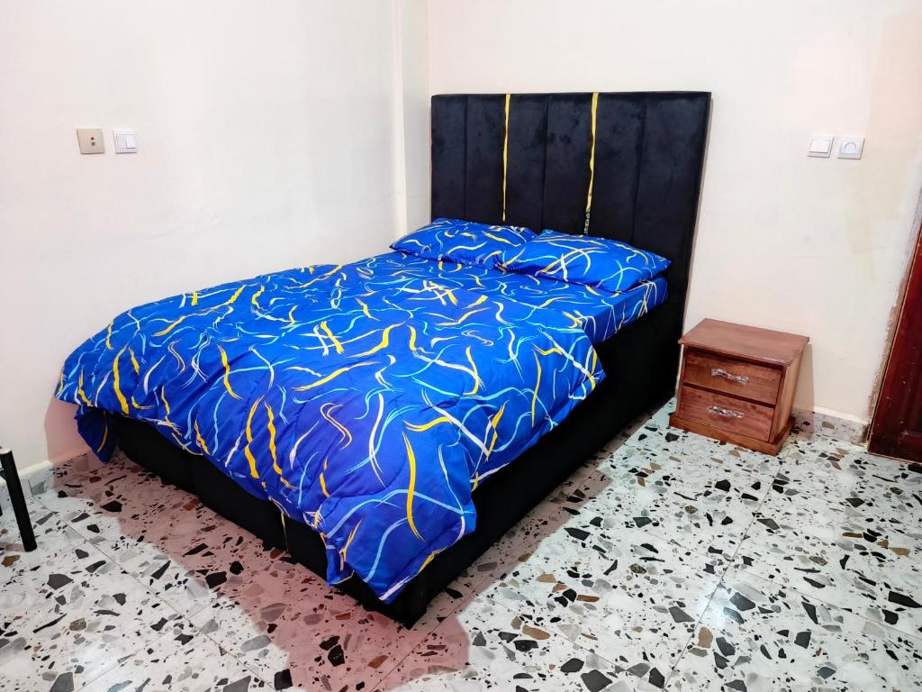1 dormitorio con cama con edredón azul y mesa en Lighthouse meublé, en Yaoundé