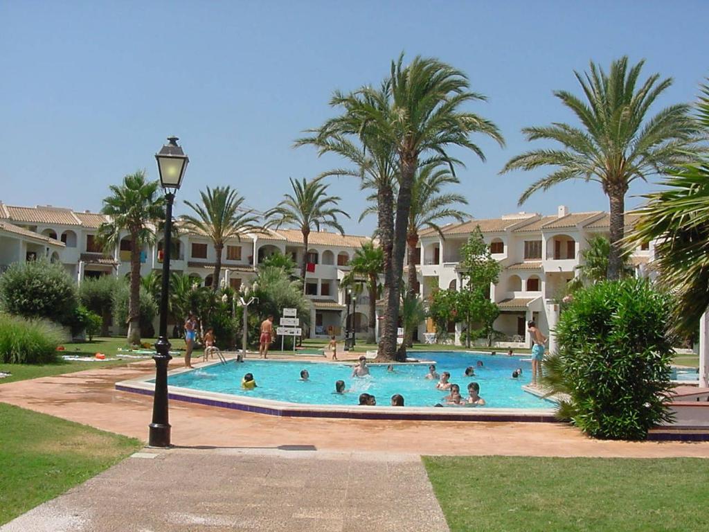 un groupe de personnes dans une piscine bordée de palmiers dans l'établissement Apartamentos Aldeas de Taray V.v., à La Manga del Mar Meno