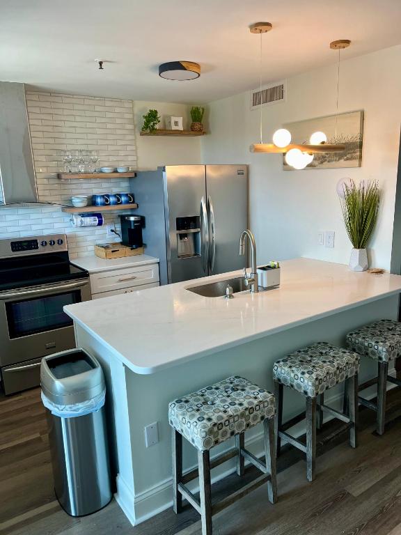 eine Küche mit einer großen Kücheninsel mit zwei Barhockern in der Unterkunft Luxe by the Sea - 5-Star Beachfront Escape in Myrtle Beach