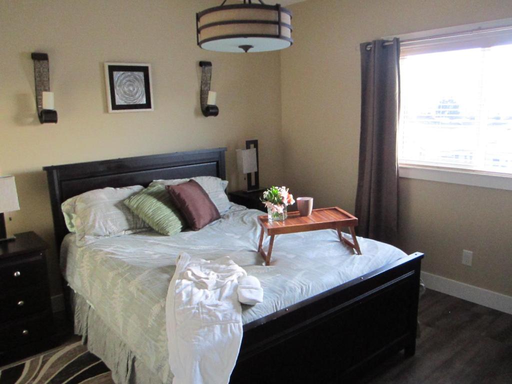ein Schlafzimmer mit einem Bett und einem Tisch darauf in der Unterkunft WineDownHere - Lic. 75806 in Kelowna