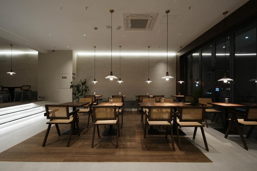 ein Esszimmer mit Tischen, Stühlen und Lichtern in der Unterkunft 画舍 Colorstory Hotel in Hangzhou