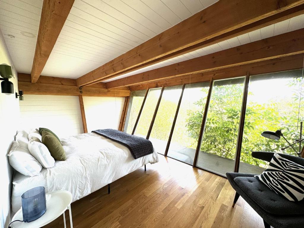 a bedroom with a bed in a room with windows at Iconic Gesner Boat House Wview Of Hollywood Sign in Los Angeles