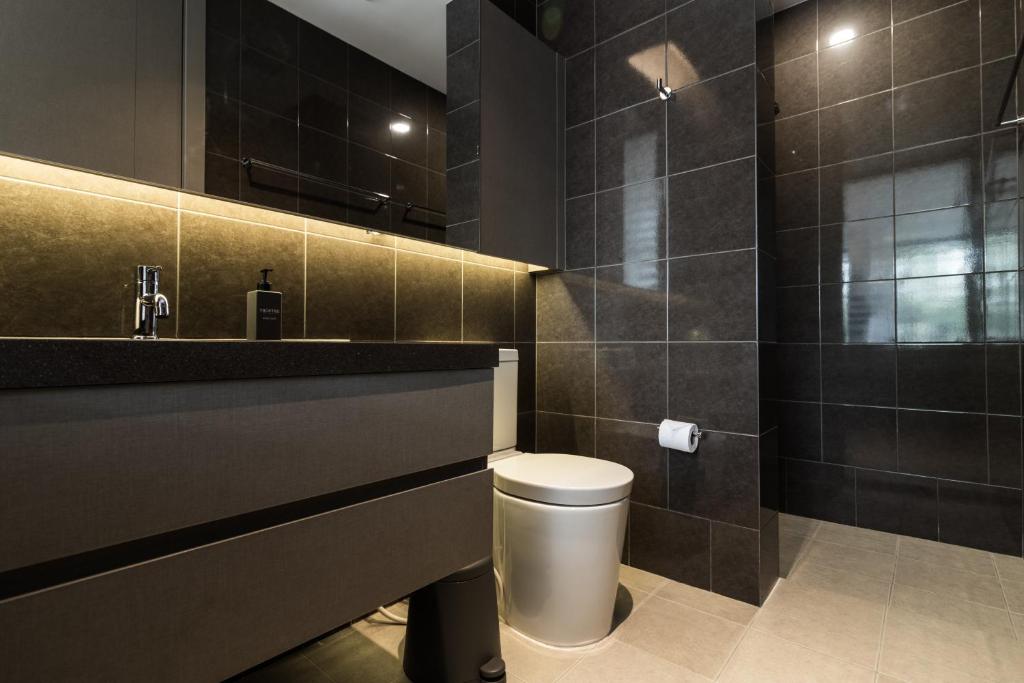 A dark-tiled bathroom with a floating vanity, toilet and walk-in shower.