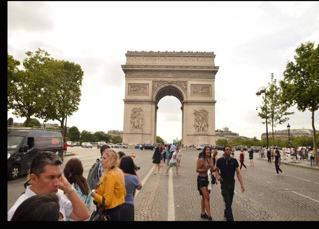 una multitud de personas caminando frente al arco del triunfo en Champs elysees apartment 4, en París