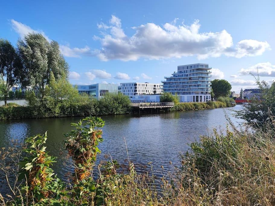 a river in front of a city with buildings at Caen au fil de l'eau in Caen