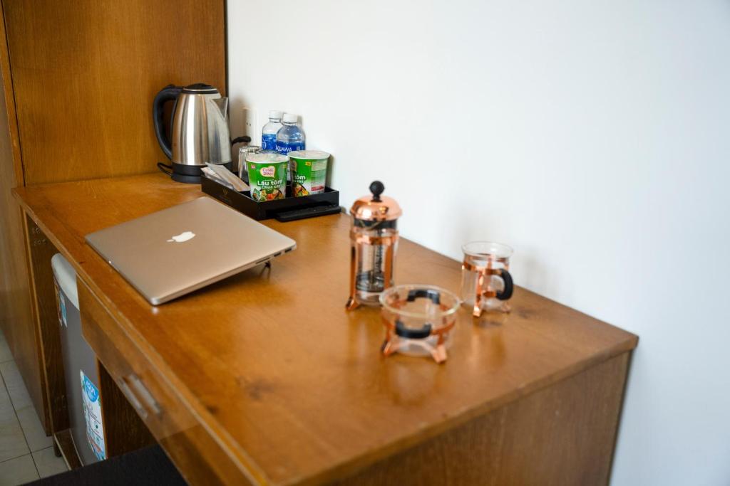 a wooden counter with a laptop and glasses on it at Trang Ngan Hotel by THG in Danang