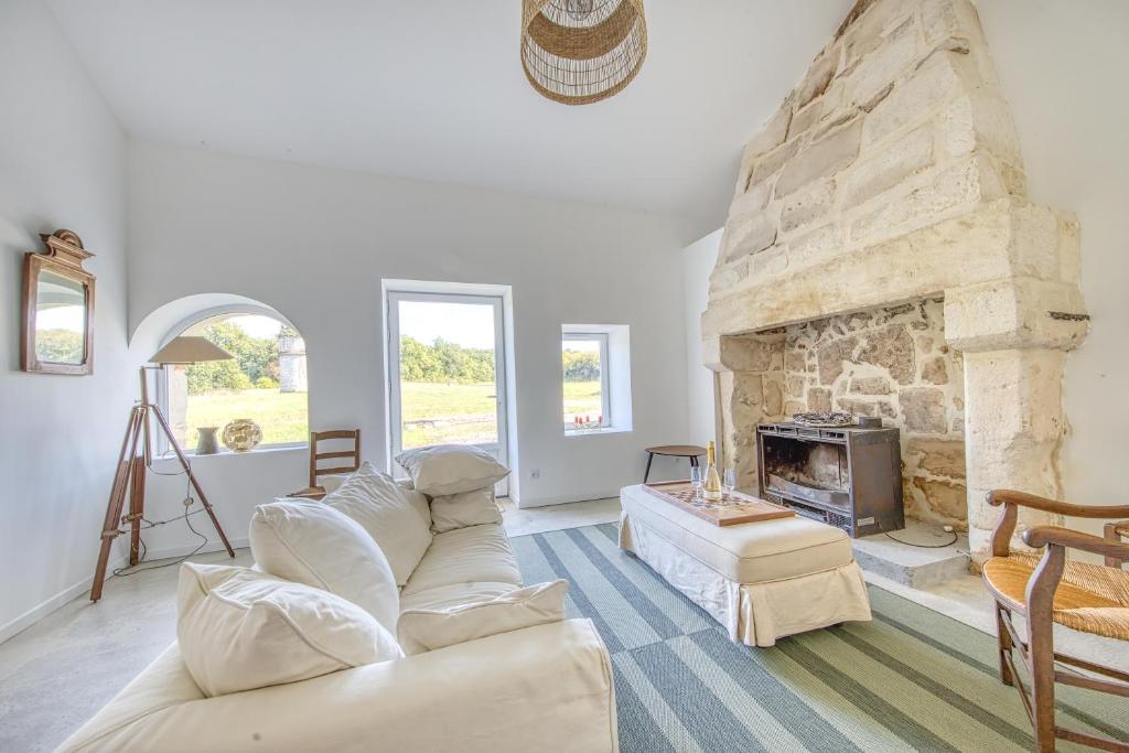 een woonkamer met een stenen open haard en een bank bij Gite De Charme - Daignac in Daignac