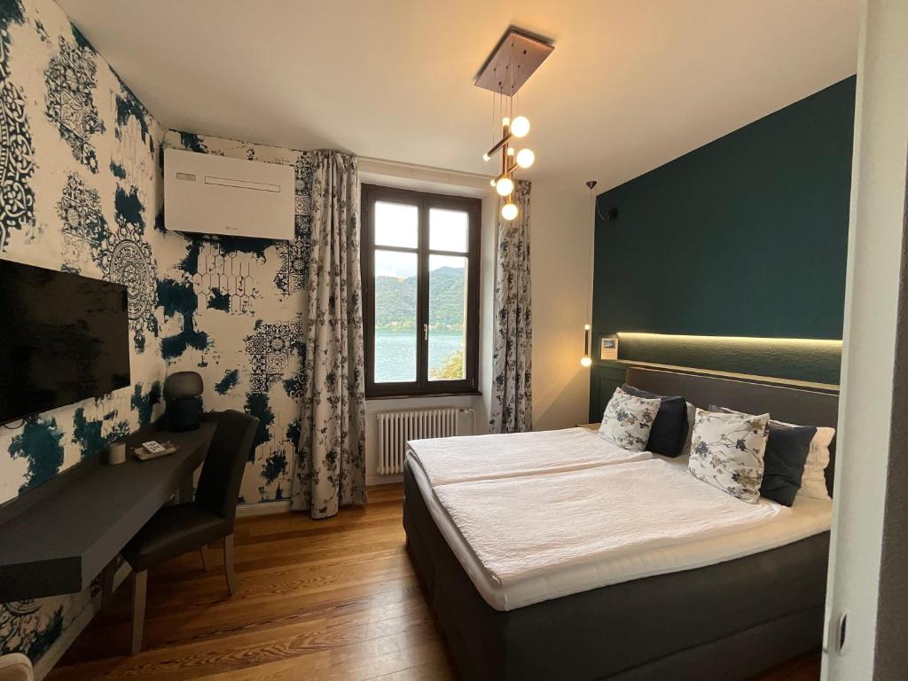 una camera con letto, scrivania e finestra di Arbostora Charme Hotel a Morcote