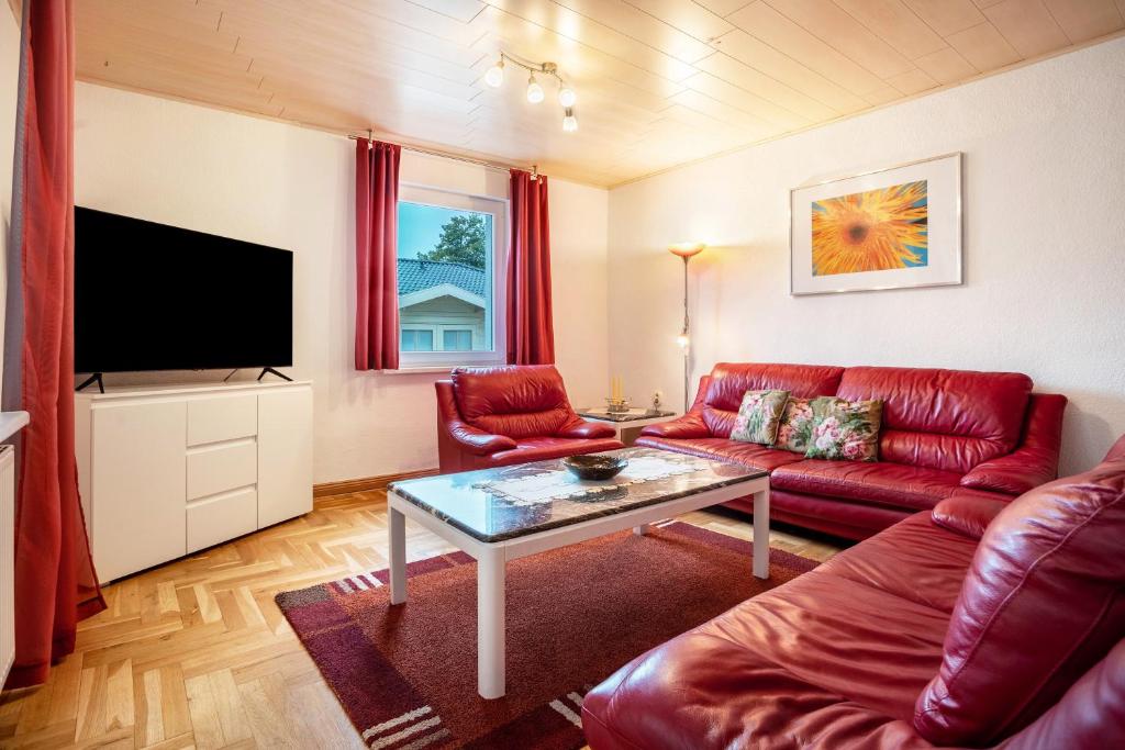 a living room with a red couch and a tv at Prerow Am Deich - Fewo 3 in Prerow