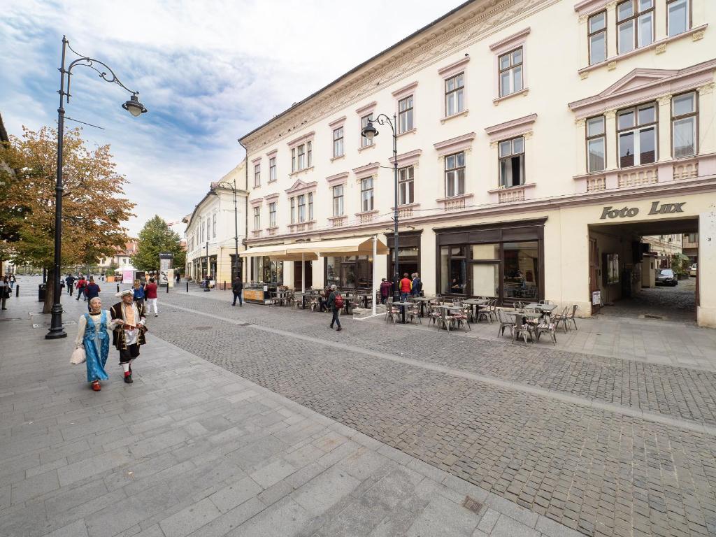 a group of people walking down a street with buildings at City Spirit Studio - Piața Mare & Bălcescu View in Sibiu